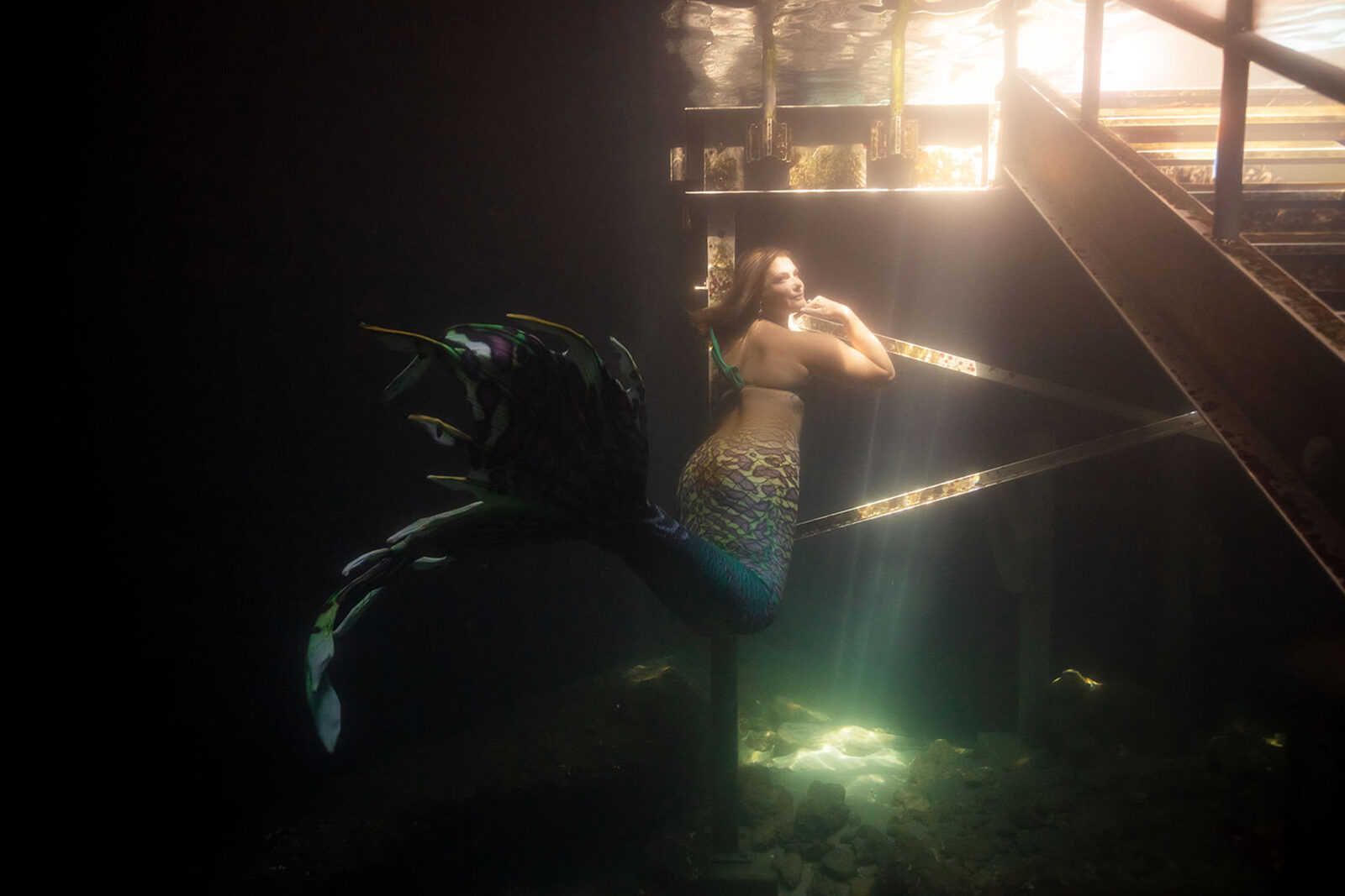 Mermaid in streaming sunlight beside the underwater entry staircase at Devil's Den Spring